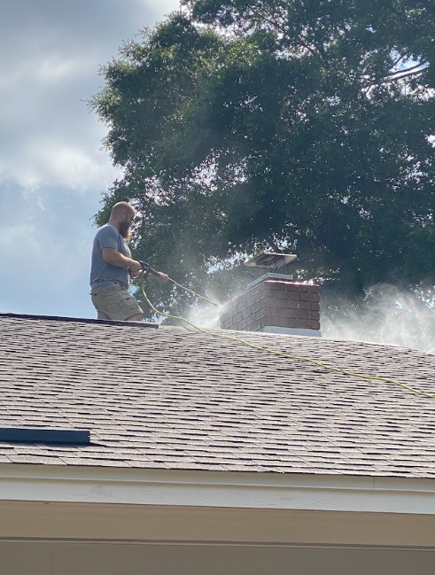 Technician pressure washing a chimney as the first step in preparing the masonry for professional waterproofing.