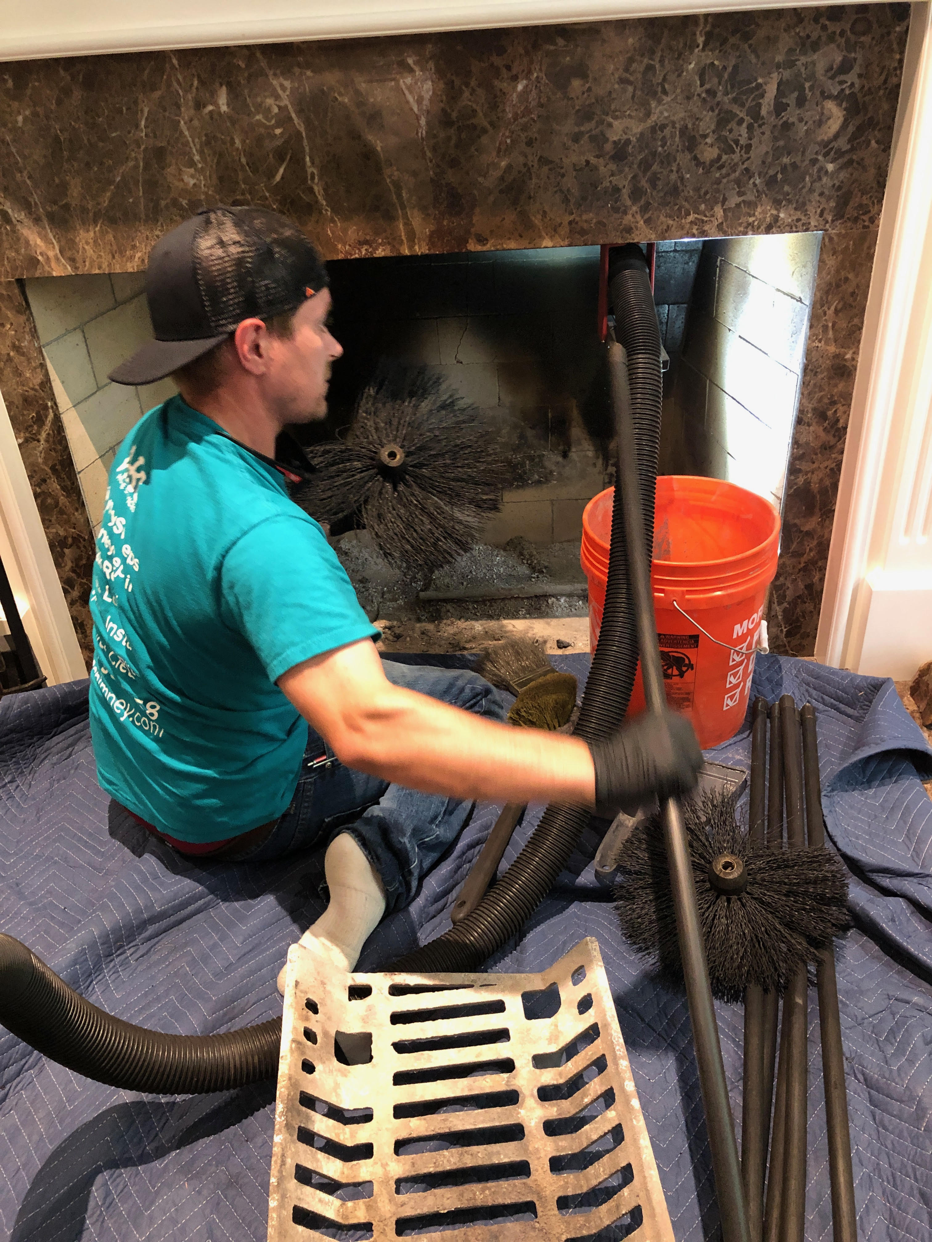 Professional chimney technician cleaning a residential chimney to remove soot and creosote buildup.