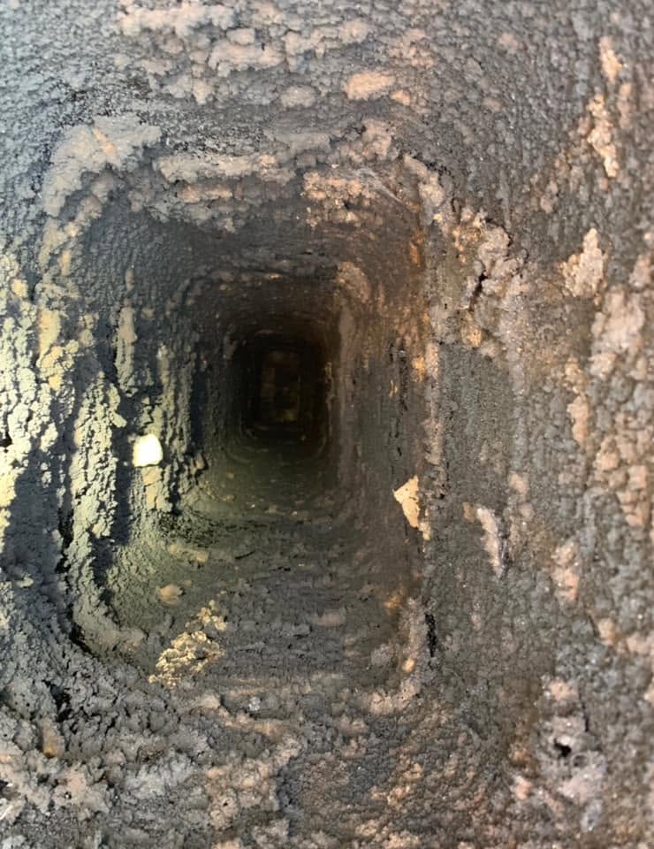 Dirty chimney flue with heavy creosote and soot buildup before professional chimney cleaning.