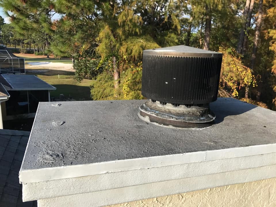 Rusted and damaged chimney chase cover with visible corrosion allowing potential water intrusion before replacement.
